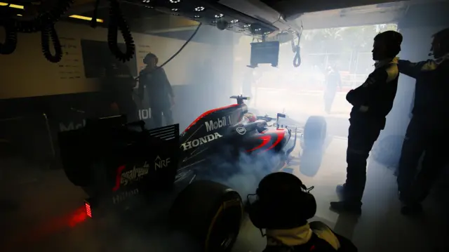 Jenson Button's McLaren smokes as it leaves the garage