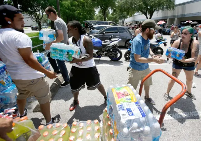 Volunteers unload cases of water and sports drinks to be donated to victims families of a shooting