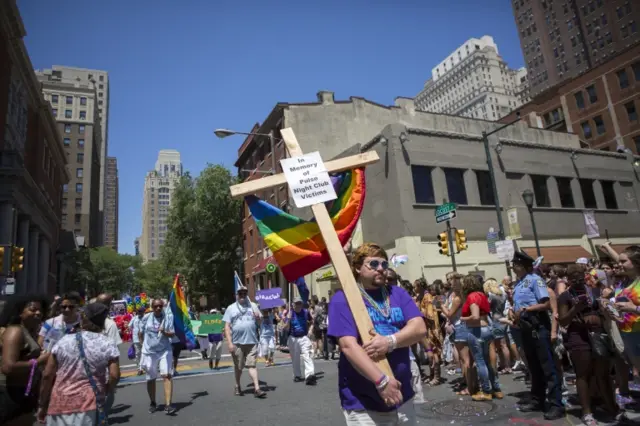 Austin Ellis, a member of Metropolitan Community Church, carries a cross with a sign in memory of the victims of the Pulse nightclub shooting as he marches in the 2016 Gay Pride Parade on June 12, 2016 in Philadelphia, Pennsylvania.