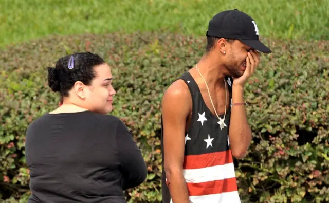 Friends and family members embrace outside the Orlando Police headquarters