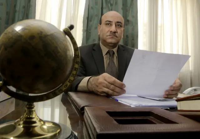 In this Tuesday, April 16, 2014 file photo, Hesham Genena, then head of Egypt's oversight body, holds documents at his office in Cairo, Egypt.