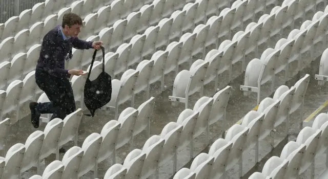 Spectators run from the rain