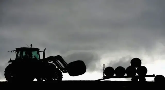 Tractor stacking hay barrels