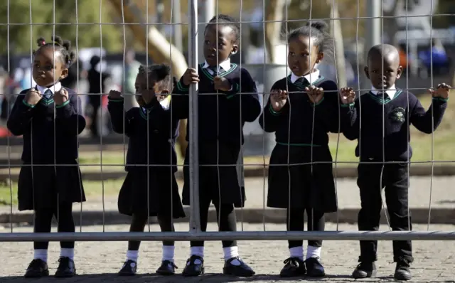 Children wearing school uniforms watch the laying of wreaths, at the Hector Pieterson Memorial in Soweto, South Africa, Thursday, June 16, 2016