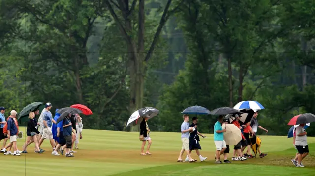 The crowd hide under umbrellas