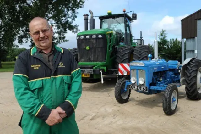 George Neeave, by his tractors in farmyard