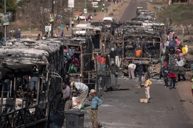 People from Mamelodi scavenge parts from the charred remain of a bus that was burnt during the 3 days long protest in Mamelodi on June 22, 2016