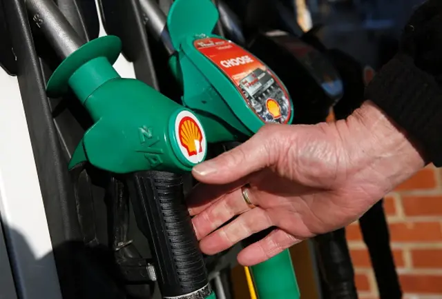 A man reaches for an unleaded petrol nosel at a fuel pump outside a Royal Dutch Shell petrol station in Hook