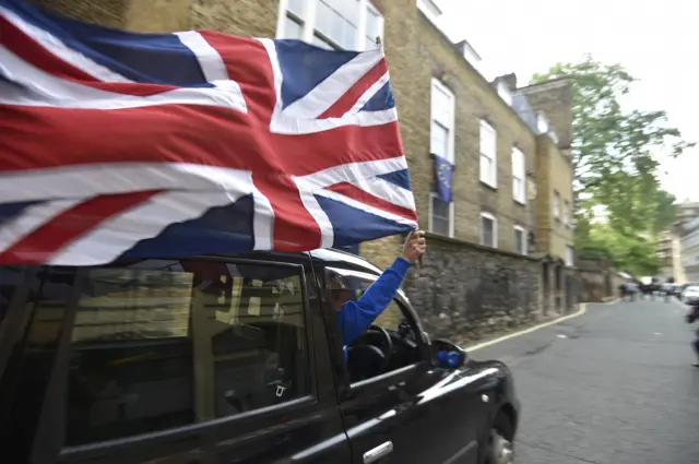 A taxi driver holds a Union flag as he celebrates the referendum result