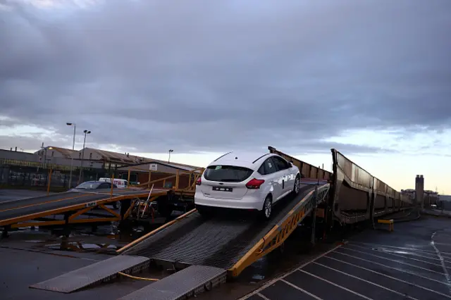 A car is loaded onto a freight train at a Ford factory