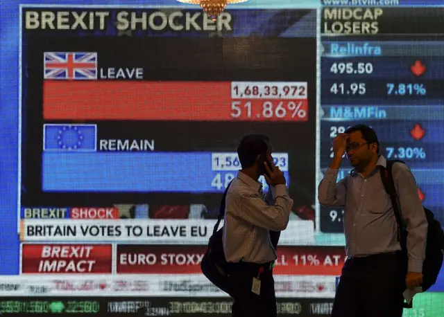 Indian men next to large screen showing news of Britain's vote to exit the European Union in Mumbai