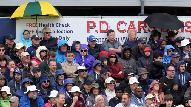 Spectators put up umbrellas