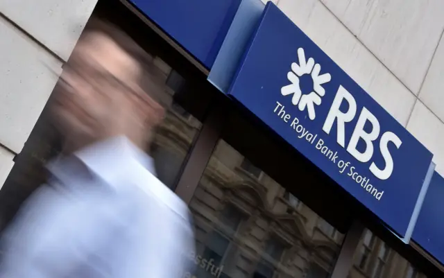 Man walks past a branch of RBS