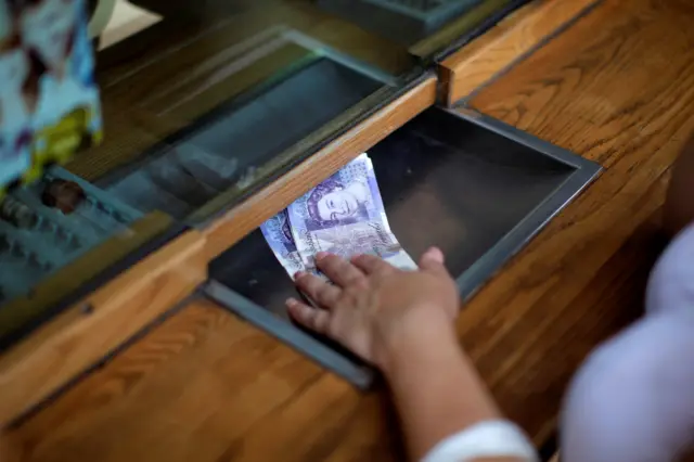 A woman exchanges £20 notes at a bank