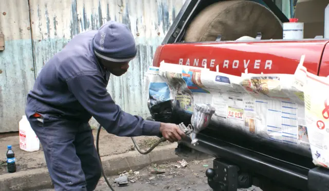 Mechanic spray paints a Land Rover