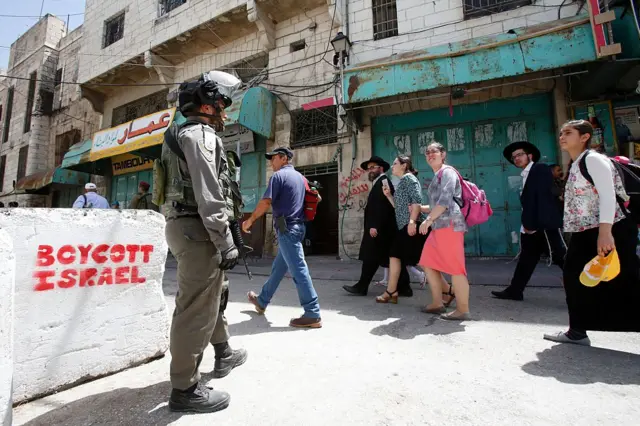 Israeli security forces escort a group of Jewish settlers through a Palestinian neighbourhood in West Bank