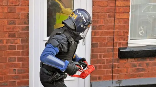 Police officer knocking down door