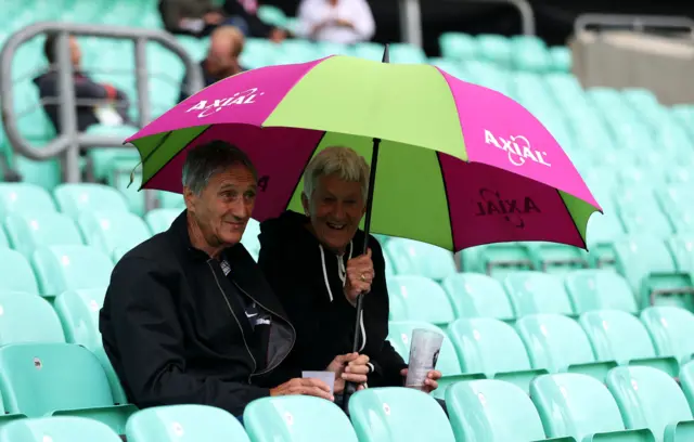 Fans hold up their umbrella