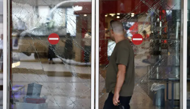 A person walks in front of broken window gates at Ataturk international airport in Istanbul, Turkey, 29 June 2016.