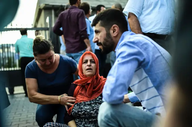 People assist a motherwho lost a relative, outside a forensic medicine building, June 29, 2016,