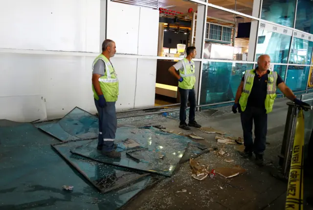 Workers stand near debris from yesterday"s blasts as they take a break at Turkey"s largest airport, Istanbul Ataturk, Turkey, June 29, 2016.