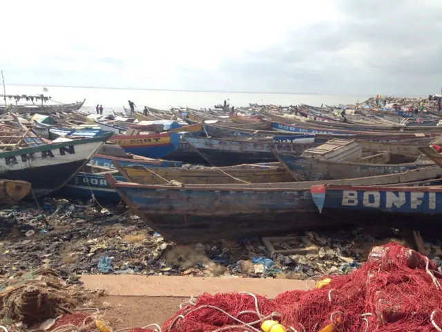 fishing nets and boats on the beach with rubbish all around