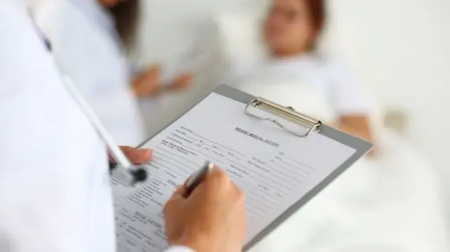 Surgeon writing notes beside patient's bed