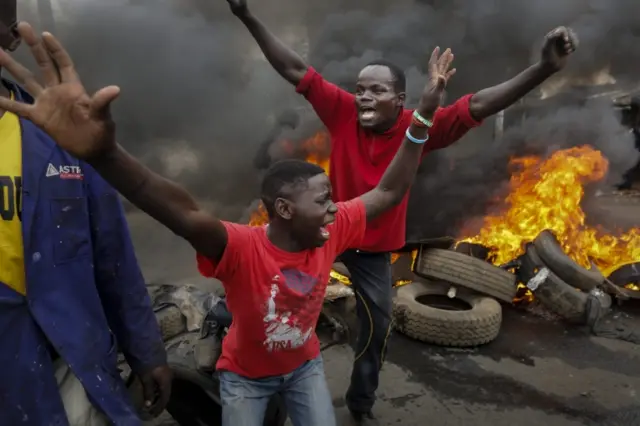 Two demonstrators in front of a burning tyre