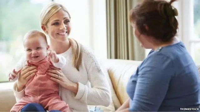 Woman holding a baby alongside another woman