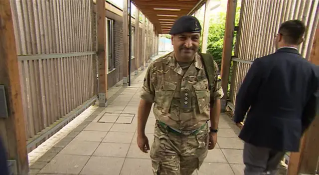 Captain Naveed Muhammad walking down a school corridor