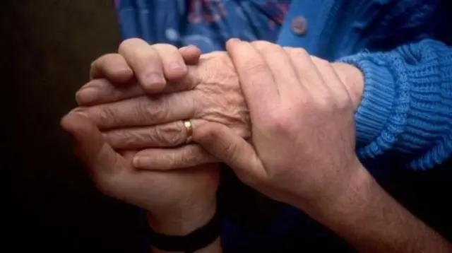 Carer holding elderly persons hand