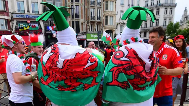 Wales fans dressed as leeks and draped in Welsh flags on the streets of Lille