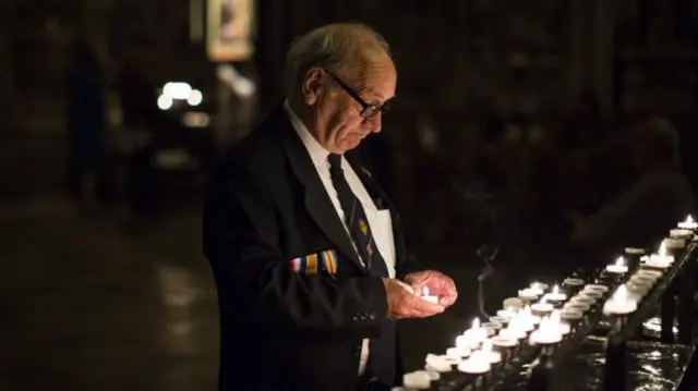 A man lights candles at Westminster Abbey