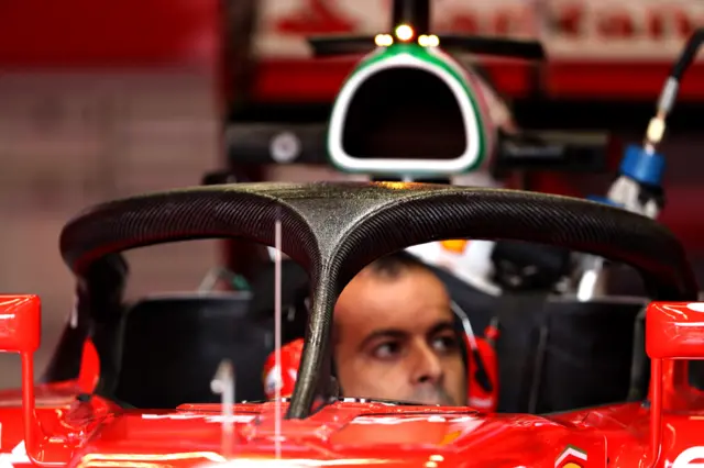 A Ferrari mechanic works on the car fitted with the halo