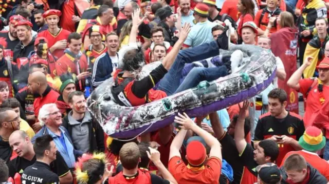 Euro 2016 fan is carried over the heads of football fans in Lille in a dinghy