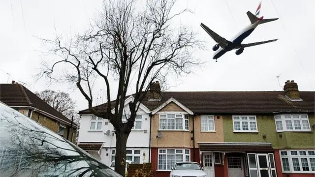 An aircraft flies over residential houses