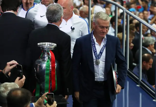 Didier Deschamps walks past the Euro 2016 trophy