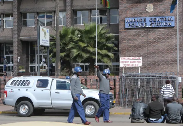 Zimbabwean anti-riot police clear journalist waiting outside the Harare Central Police station in Zimbabwe, July 12, 2016