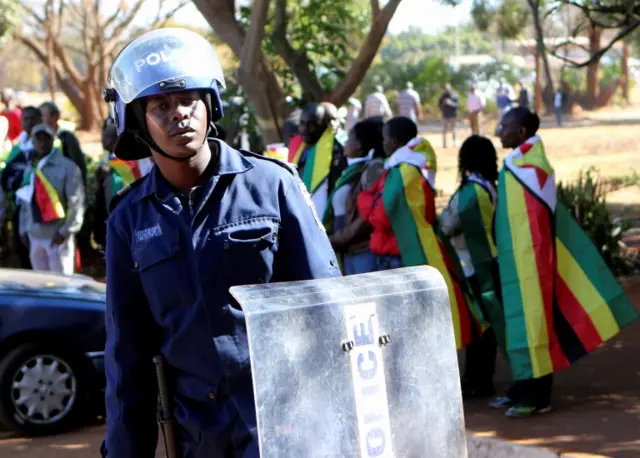 A Zimbabwean anti-riot police stand guard outside the Harare Magistrates court before the arrival of arrested Pastor Evan Mawarire, in the capital Harare, Zimbabwe