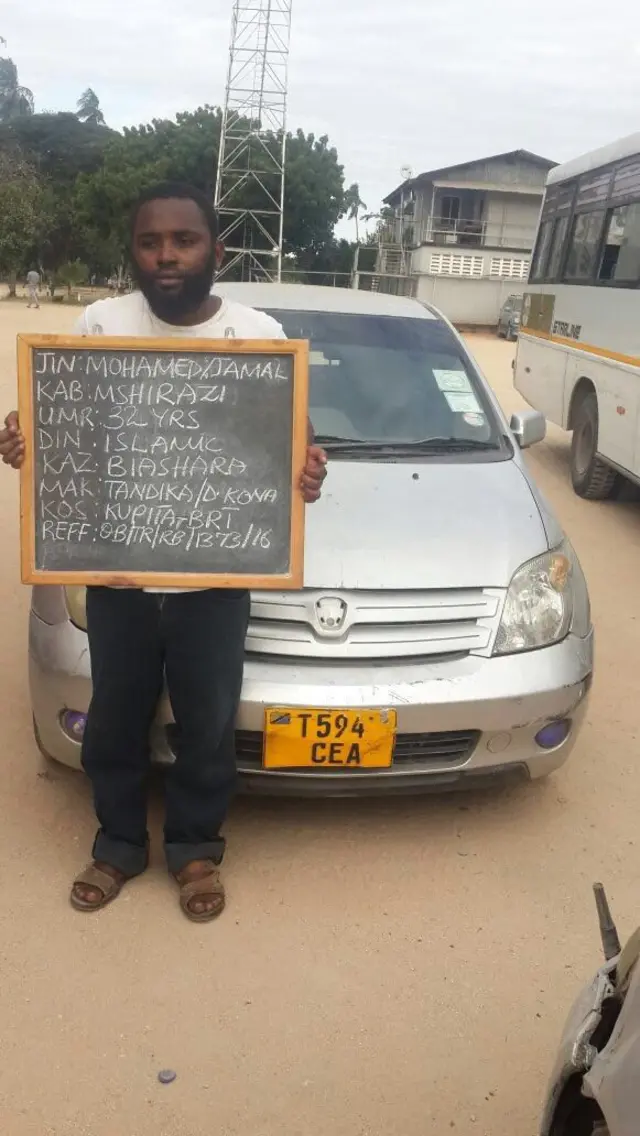 Motorist standing with chalk board with his details and traffic violation displayed in chalk