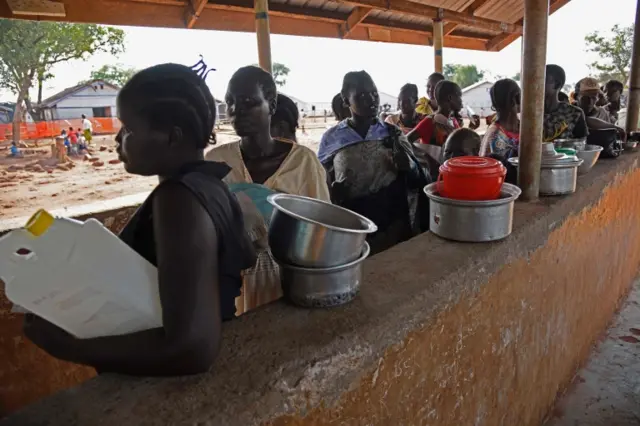 Newly arrived refugees from South Sudan queue to receive food at the Nyumanzi transit centre in Adjumani on July 13, 2016.