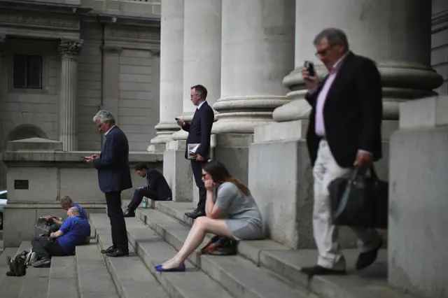 City workers talk on their mobile phones near the Bank of England