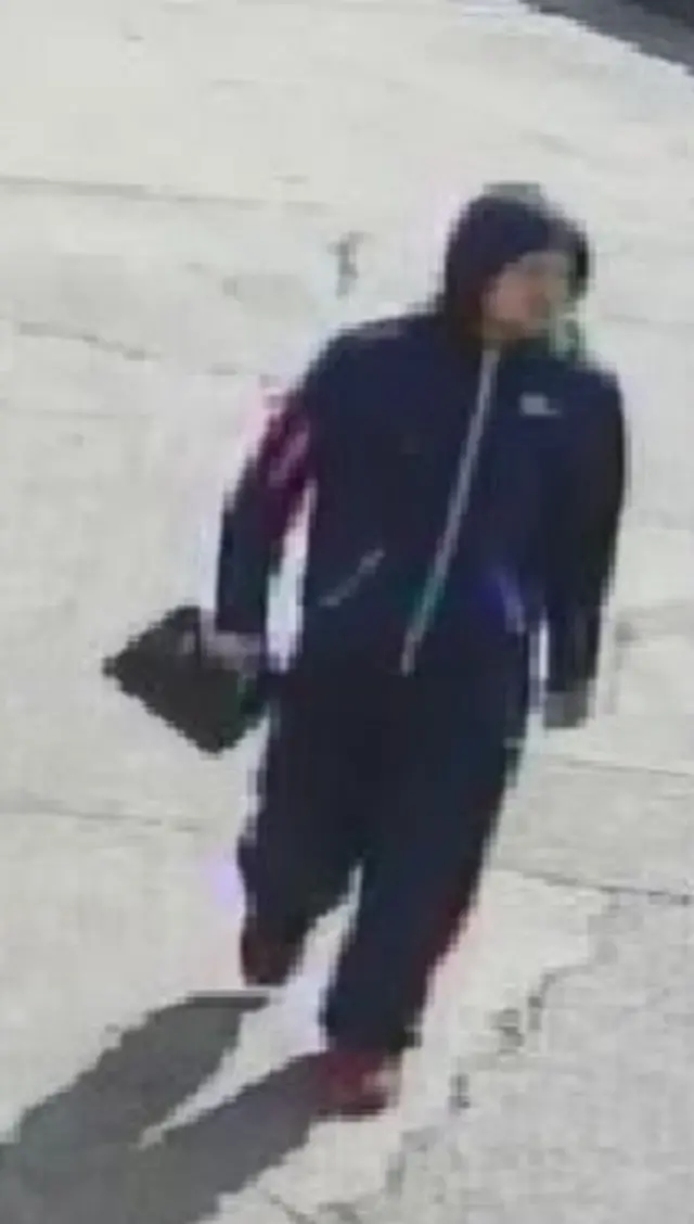 Blurred CCTV image of man carrying a jerry can