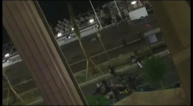 View from window of people standing near bodies on the road