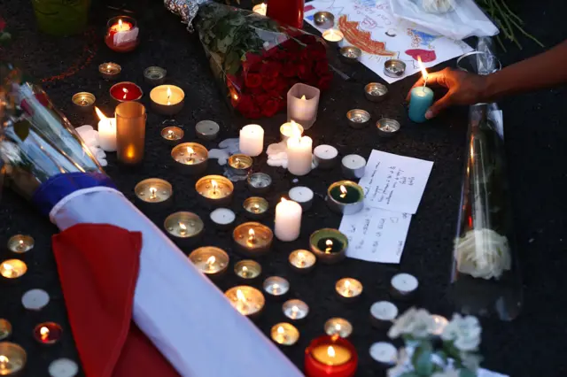 A woman places a candle in front of a memorial on the "Promenade des Anglais" where the attack happened