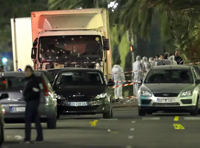 French police forces and forensic officers stand next to a truck in Nice