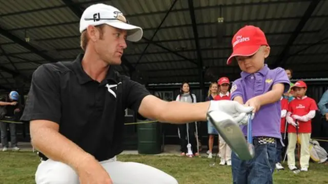 A child being shown how to swing a golf club