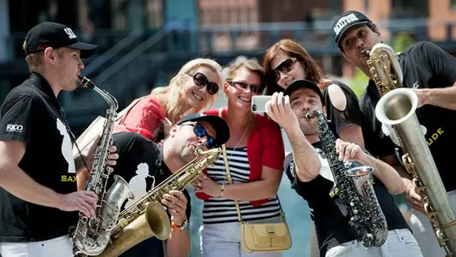 Saxophonists taking a selfie with three spectators