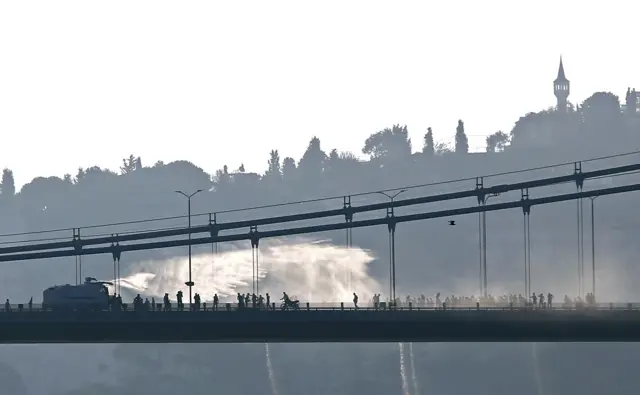 A police armored vehicle uses a water cannon to disperse anti-goverment forces on Bosphorus Bridge in Istanbu