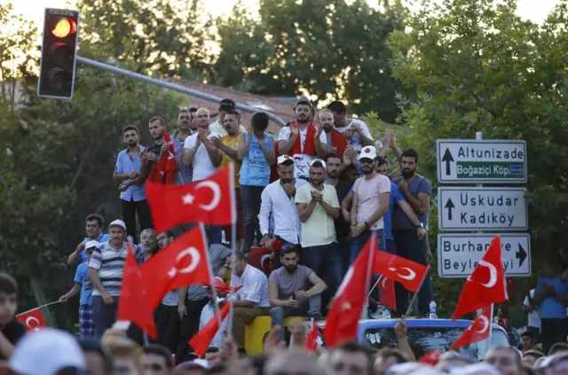 People wait for Turkish President Tayyip Erdogan to appear for a speech outside his residence in Istanbul, Turkey